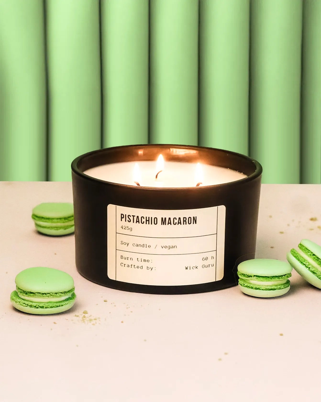 Pistachio macaron candle with green macarons on a light surface and green curtain background