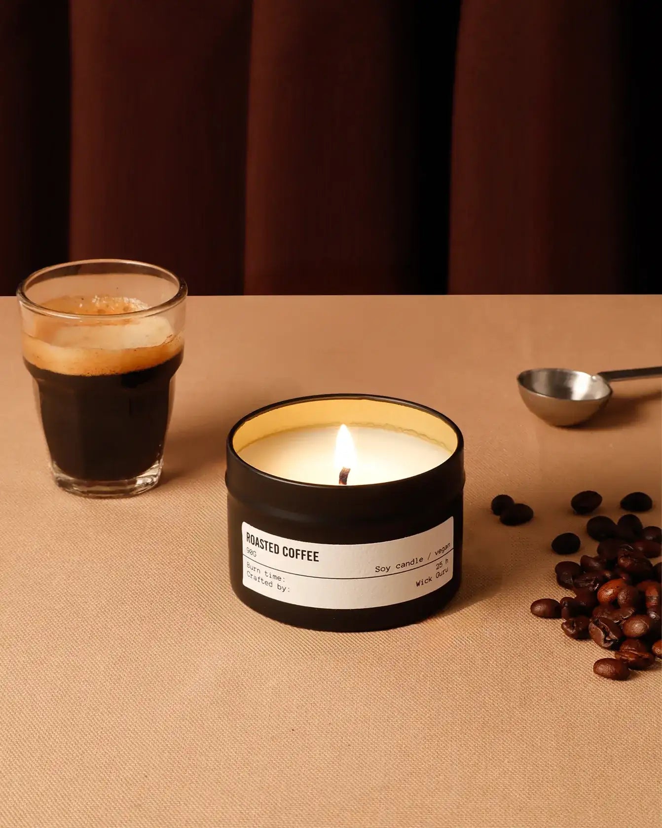 Candle labeled 'Roasted Coffee' with a glass of coffee and coffee beans on a brown surface