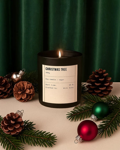 Black candle labeled 'Christmas Tree' with decorative pinecones and ornaments on a green curtain background