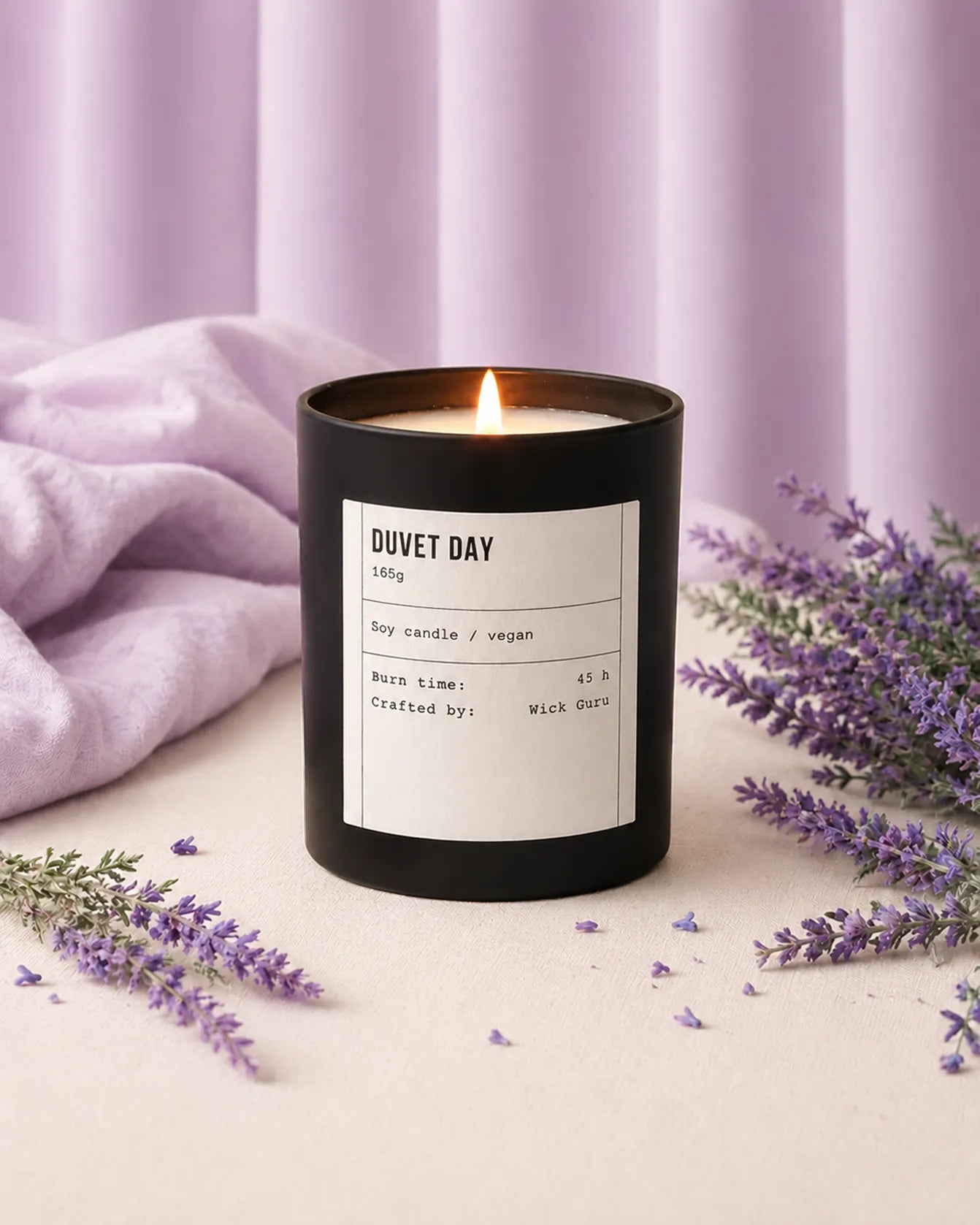 Black candle labeled 'Duvet Day' with lavender flowers on a light background
