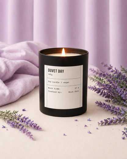 Black candle labeled 'Duvet Day' with lavender flowers on a light background