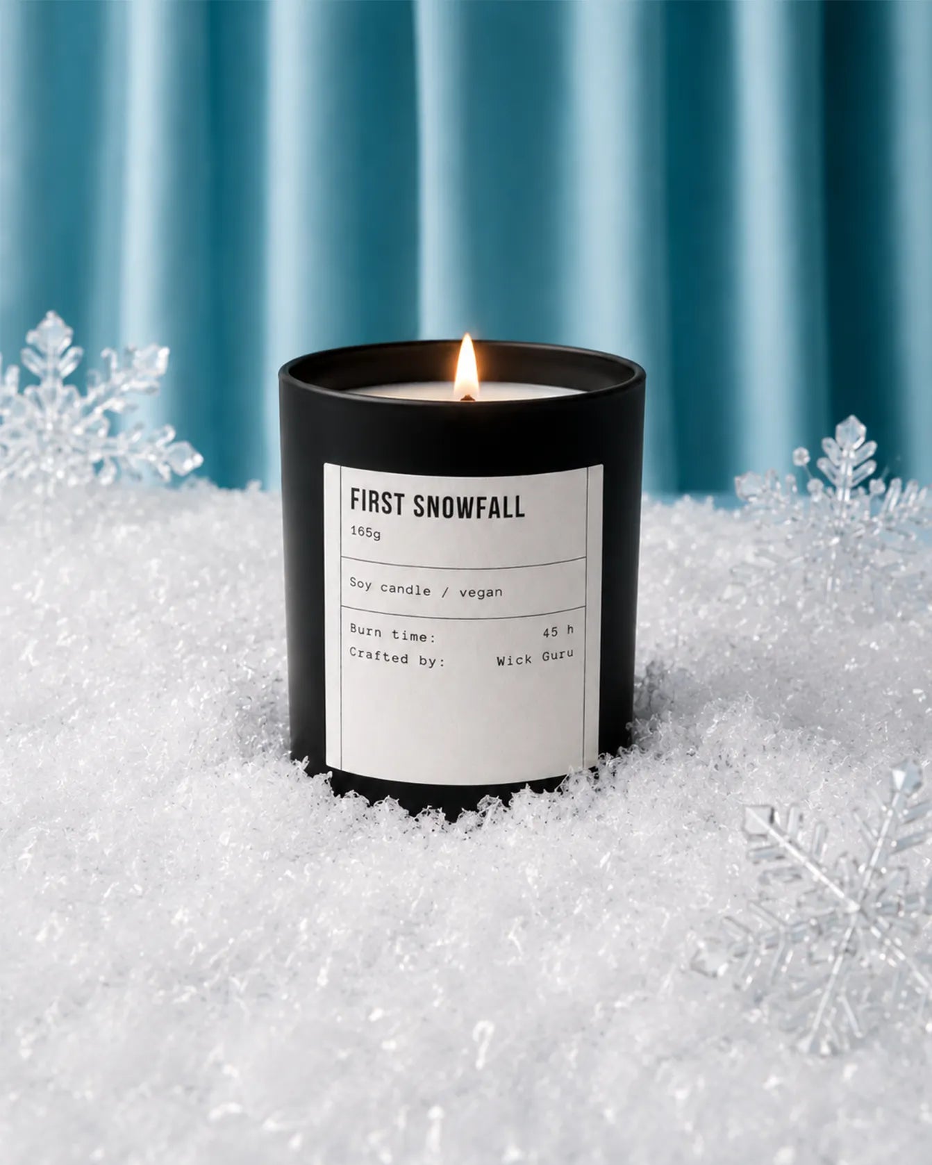Candle labeled 'First Snowfall' in a snowy setting with snowflakes.