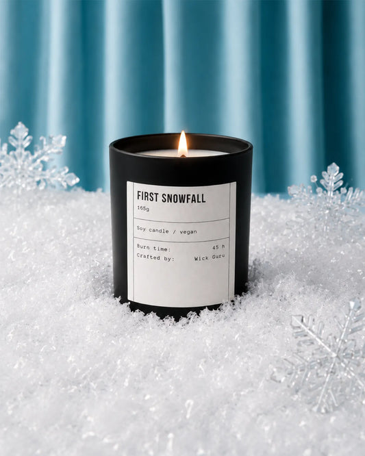 Candle labeled 'First Snowfall' in a snowy setting with snowflakes.
