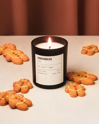 Candle labeled 'Gingerbread' with gingerbread cookies on a white surface