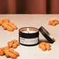 Candle in a tin labeled 'Gingerbread' surrounded by gingerbread cookies on a neutral background