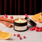 Candle with cinnamon sticks, oranges, and berries on a neutral background