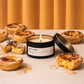 Candle labeled 'Pastel de Nata' surrounded by Portuguese pastries on a neutral background