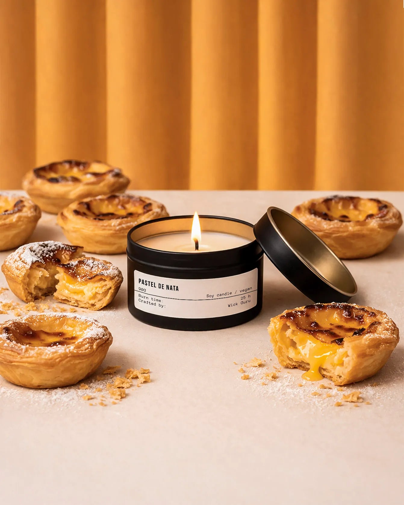 Candle labeled 'Pastel de Nata' surrounded by Portuguese pastries on a neutral background