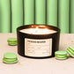 Pistachio macaron candle with green macarons on a light surface and green curtain background