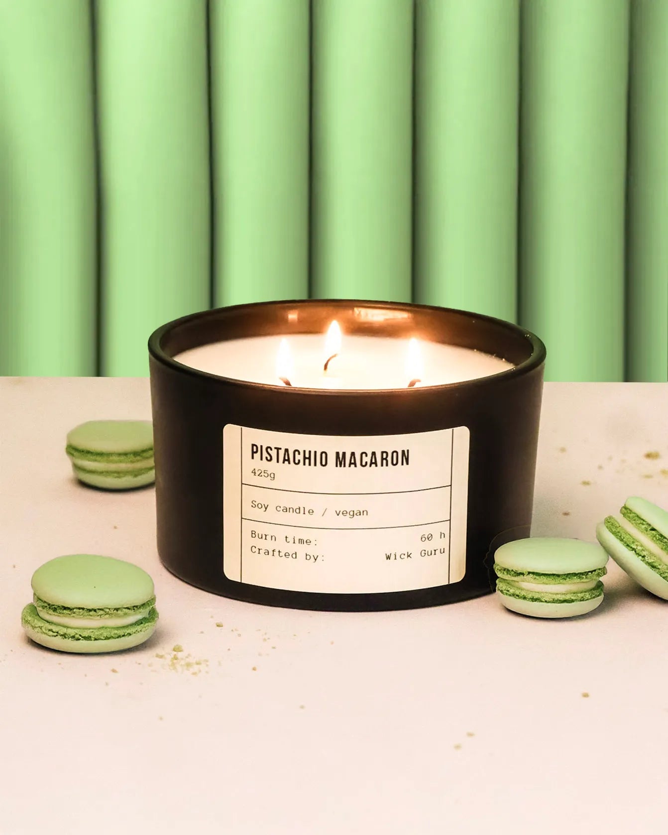 Pistachio macaron candle with green macarons on a light background