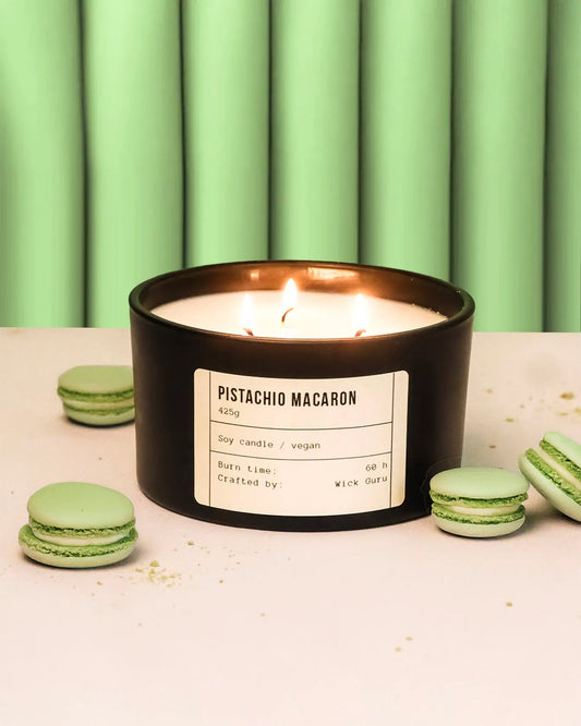 Pistachio macaron candle with green macarons on a light background