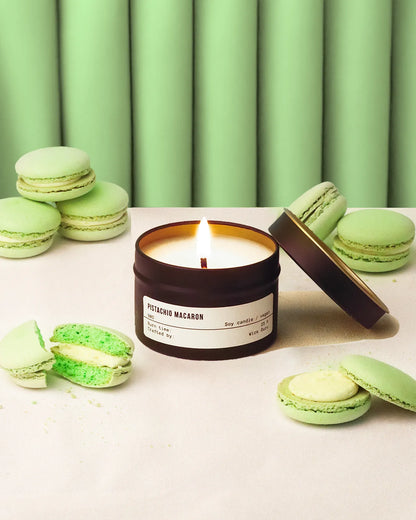 Green macaron candle with macarons on a light surface and green curtain background