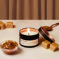 Candle labeled 'Salted Caramel' with caramel sauce and pieces on a neutral background