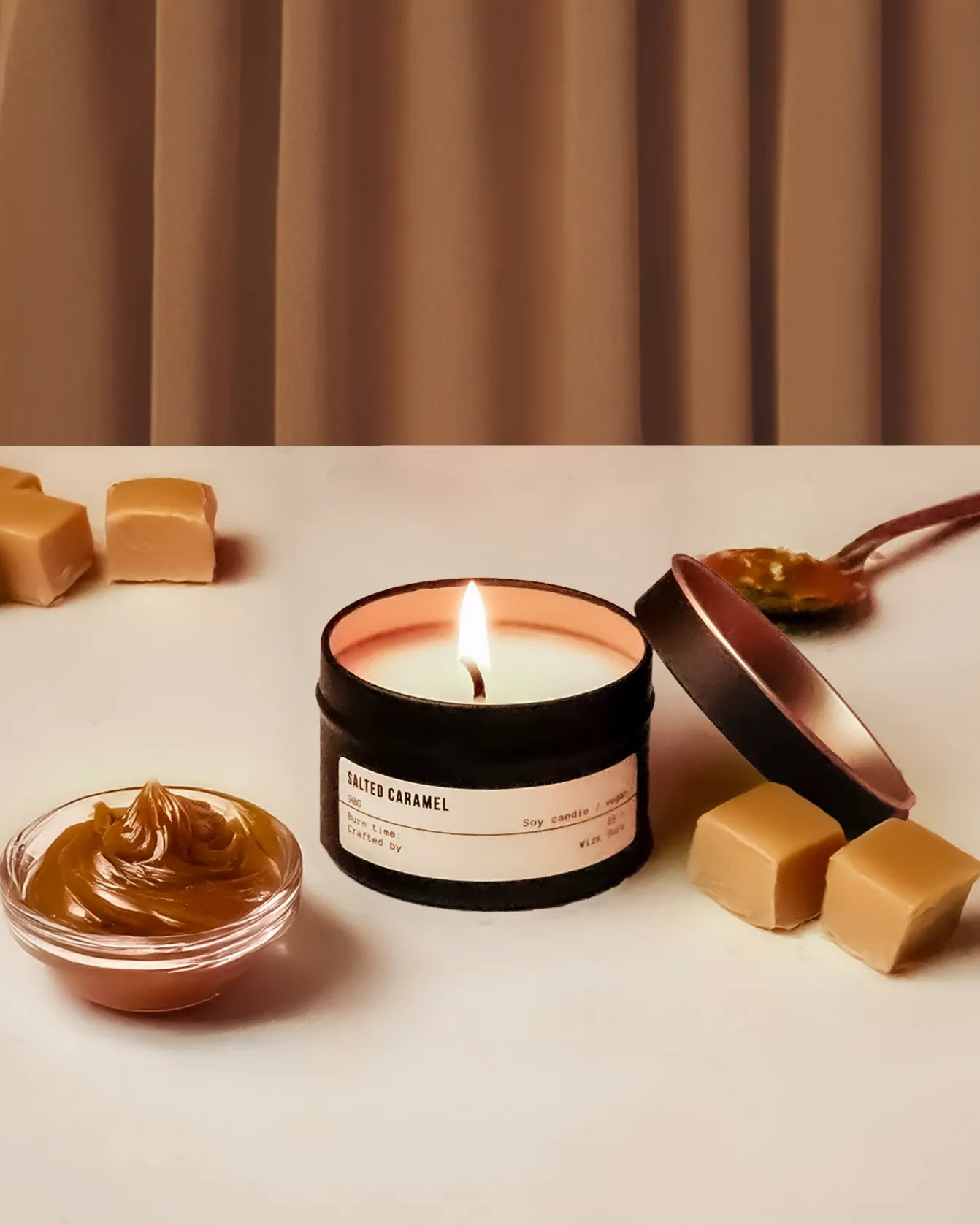 Candle labeled 'Salted Caramel' with caramel sauce and pieces on a neutral background