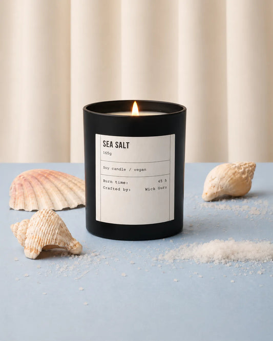 Sea Salt candle with shells and sand on a light blue surface