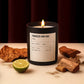 Candle labeled 'Tobacco and Oak' with wooden elements and a lime on a beige surface.