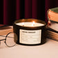 Candle labeled 'Vintage Bookshop' on a surface with books and glasses in the background