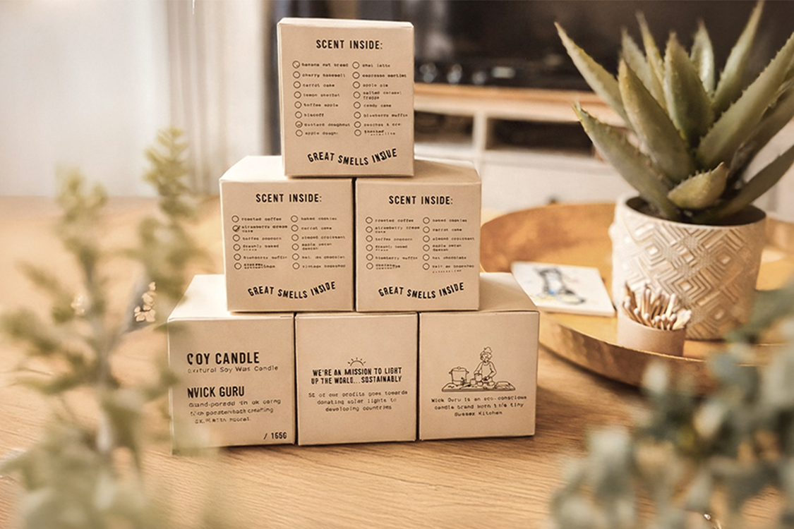 Stack of cardboard boxes with text and branding on a wooden surface with plants in the background